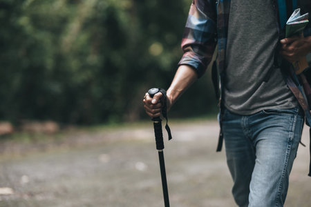 Hikers use trekking pole with backpacks and hold tent bag walking through the forest. hiking and adventure concept.の写真素材