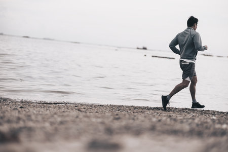 healthy lifestyle young fitness man running at seaside beach. Outdoor workout,  Healthy lifestyle concept.の写真素材