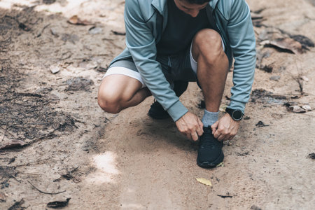 Sport man  tying jogging shoes in the forest. Outdoor workout,  Healthy lifestyle concept.の写真素材
