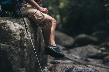 hiker with backpack sitting on the rock in waterfall while a rest. hiking and adventure concept.の写真素材