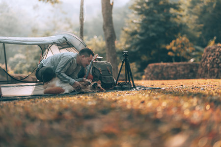 Man playing with dog in the morning during a camping trip in the forest on holiday. Vocation and travel concept.の写真素材