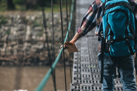 Hikers use trekking pole with backpacks and hold map walking through the bridge in the forest. hiking and adventure concept.の写真素材