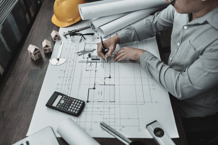 Architect engineer use pen and mini T-slide drawing design working on blueprint. House planning...