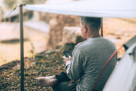 Man playing drink coffee in the morning during a camping trip in the forest on holiday. Vocation and travel concept.の写真素材