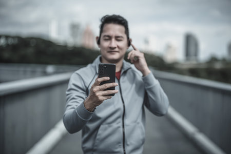 sport man listen music earphone and  use smartphone Fitness application, social media, listening to music. Health and Lifestyle in big city life concept.の写真素材