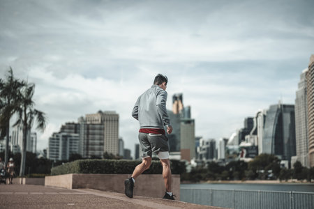 A man  running down on stairs in the city center park before cardio workout.  Health and Lifestyle in big city life concept.の写真素材