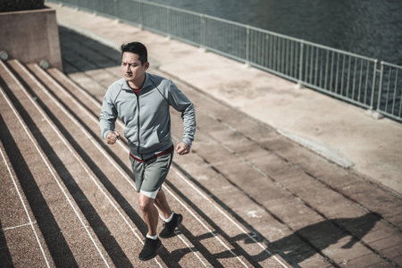 A man  running up on stairs in the city center park for cardio workout.  Health and Lifestyle in big city life concept.の写真素材