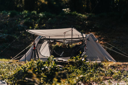 camping lantern Hanging on poles and tents pitched on hillsides beside streams of water from waterfalls.  hiking bag, hiking shoes, trekking pole on the ground.の写真素材