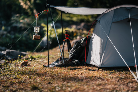 tents pitched on hillsides beside streams of water from waterfalls. hiking bag, hiking shoes on the ground.の写真素材