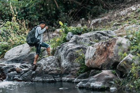 Hikers walk on rocks with dog in the stream flowing from the waterfall bact to his tent in hill.の写真素材