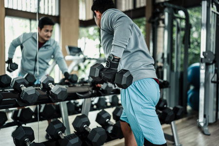 A man doing exercises triceps muscle with dumbbell in gym. Fitness, workout and traning concept.の写真素材
