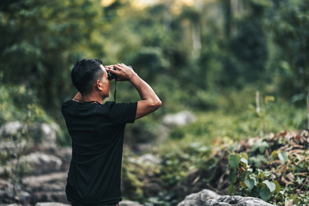 Hikers use binocular to see animals and view landscape with backpacks in the forest. hiking and...