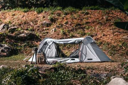 tents pitched on hillsides beside streams of water from waterfalls. hiking bag, hiking shoes on the ground.の写真素材