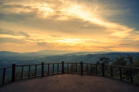 The wooden balcony has a view of the mountains and sunset behind.の写真素材