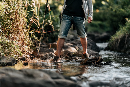 Hikers walk on rocks in the stream flowing from the waterfall in the forest.の写真素材