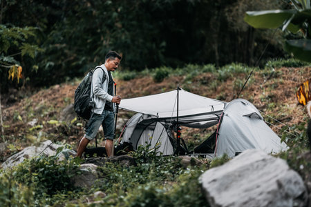 Hikers walk on rocks with dog in the stream flowing from the waterfall bact to his tent in hill.の写真素材