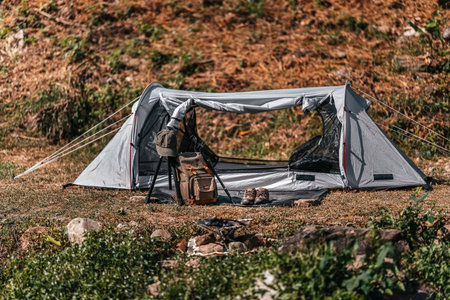 tents pitched on hillsides beside streams of water from waterfalls. hiking bag, hiking shoes on the ground.の写真素材