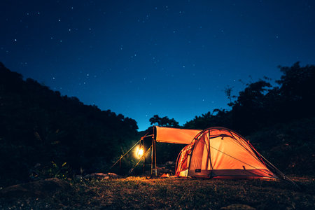 tents pitched on hillsides beside streams of water from waterfalls at night under star in the sky.の写真素材