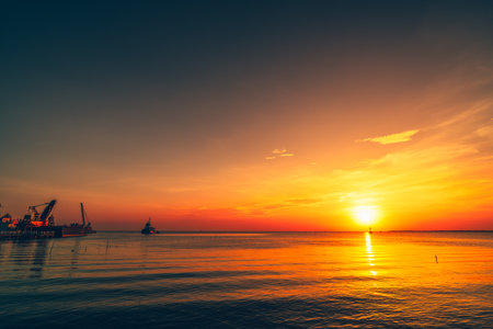 Serene Sunset Over the Open Ocean with Calm Reflecting Waters.の写真素材