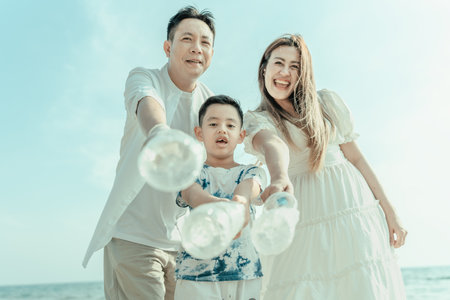 Plastic bottles collected from the beach are carried by the Asian family to be thrown in the trash, Them clean and dirty beach.の写真素材