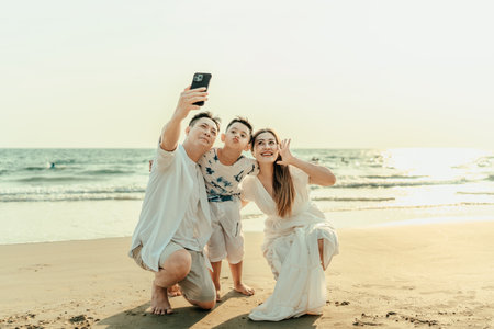 Family, parents, children, smiling happiness Take photos together with cell phone on the beach during holidays, travel, long weekends, summer or other holidays.の写真素材