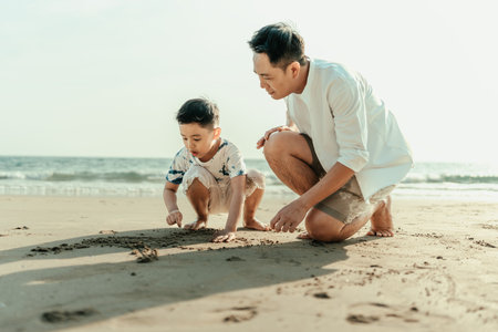 The father and son write in the sand while on vacation, traveling, or a long weekend. They are happy to spend time together.の写真素材