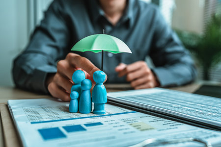A wooden doll under an umbrella holding by agent represent insurance . Family , protection, life.の写真素材