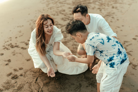 Families explore the sand, look at crabs, and find seashells on the beach during holidays, travel, long weekends, summers, or other vacations. They are happy to spend time together.の写真素材