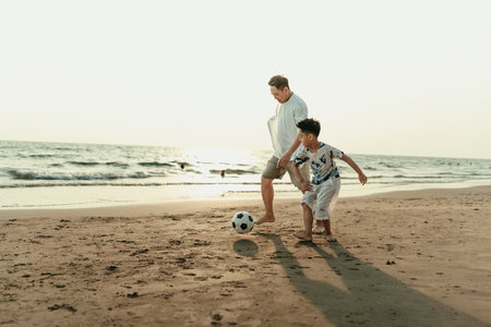 Father and son play football happiness on the beach during vacation, travel, long weekend, summer or any other holiday. They are happy to spend time together.の写真素材