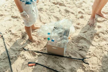 A father and son are removing trash from the beach and putting it in boxes for recycling. Family...