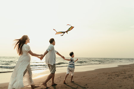 Children flying kites on the beach with family during vacation, travel, long weekend, summer or other holidays. They are happy to spend time together.の写真素材