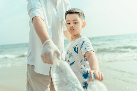 Plastic bottles collected from the beach are carried by the father and son to be thrown in the trash, both clean and dirty beaches.の写真素材