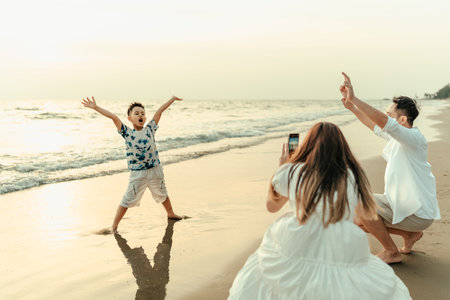 During vacation, travel, long weekend, summer, or other holidays, children are happiness to be with their family while raising their hands and shouting on the beach.の写真素材
