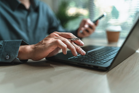 Businessman is hand holding pen working and typing on laptop. Business report graph and chart, corporate, finance and marketing concept.の写真素材