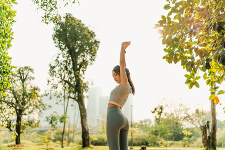 A woman dressed in workout clothes is wearing headphones and listening to music while stretching her muscles before exercising, before running, or after exercising.の写真素材