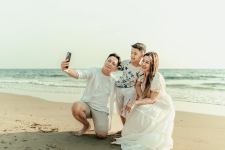 Family, parents, children, smiling happiness Take photos together with cell phone on the beach during holidays, travel, long weekends, summer or other holidays.の写真素材