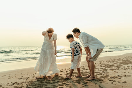 Families explore the sand, look at crabs, and find seashells on the beach during holidays, travel, long weekends, summers, or other vacations. They are happy to spend time together.の写真素材