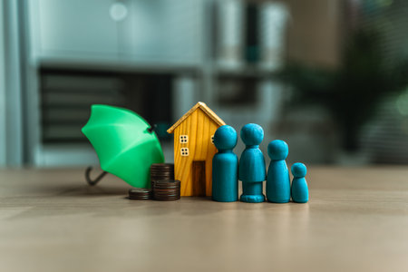 Money, a house, a wooden doll represent family and an umbrella. All meanings related to insurance.の写真素材