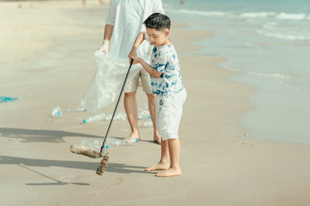 On the beach, a father and son carry bags to collect trash. Clean up the dirty sea or ocean and collect reusable plastic bottles. Garbage recycling.の写真素材