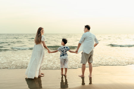 On vacation, travel, or a long weekend, spend time together with family happiness and hand in hand on a beautiful beach with sunset light.の写真素材