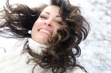 Outdoor portrait of a young pretty brunette wearing a white warm sweater.の写真素材