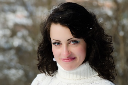 Outdoor portrait of a young pretty brunette wearing a white warm sweater.の写真素材
