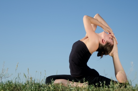Yoga woman on green grass  Sky background の写真素材