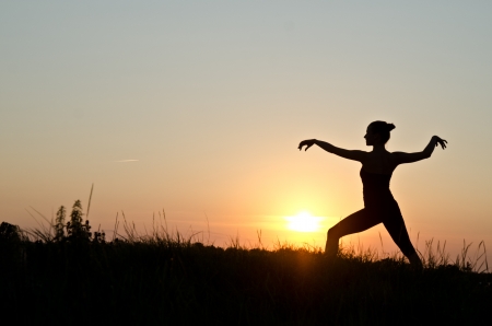 Woman praticing tai chi chuan at sunset.の写真素材