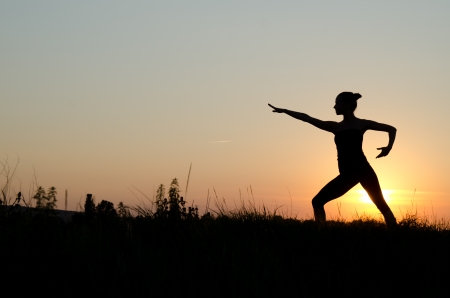 Woman praticing tai chi chuan at sunset.の写真素材