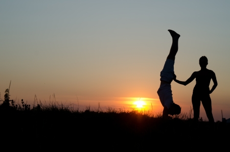 Acrobatic couple. Silhouette, sunset.の写真素材