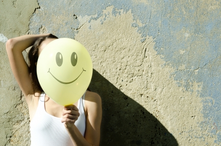 Yellow balloon with smile and  girl, wall background.の写真素材