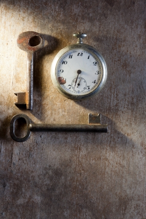 Pocket-watch and rusty keys on wooden texture background.の写真素材