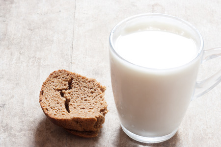 bread and mug of milk on wooden tableの写真素材