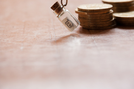 New house buy concept. House drawing in a glass jar and gold coins.の写真素材